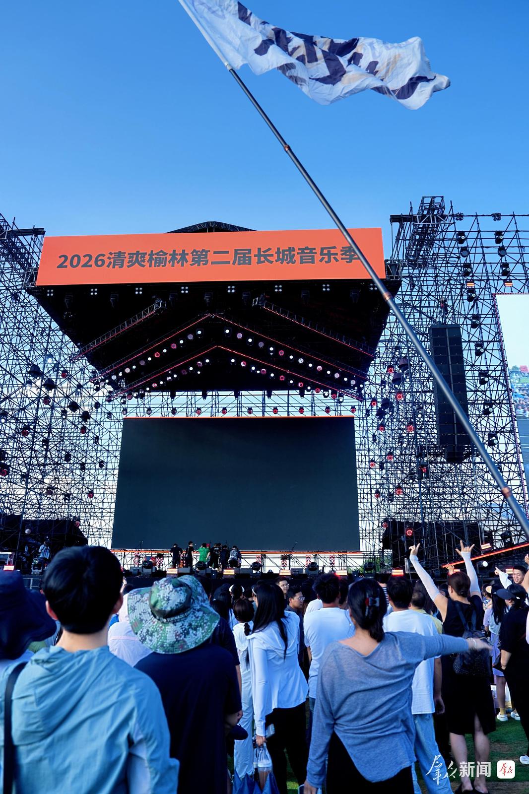 歌迷挥舞旗帜与台上的乐队合影。