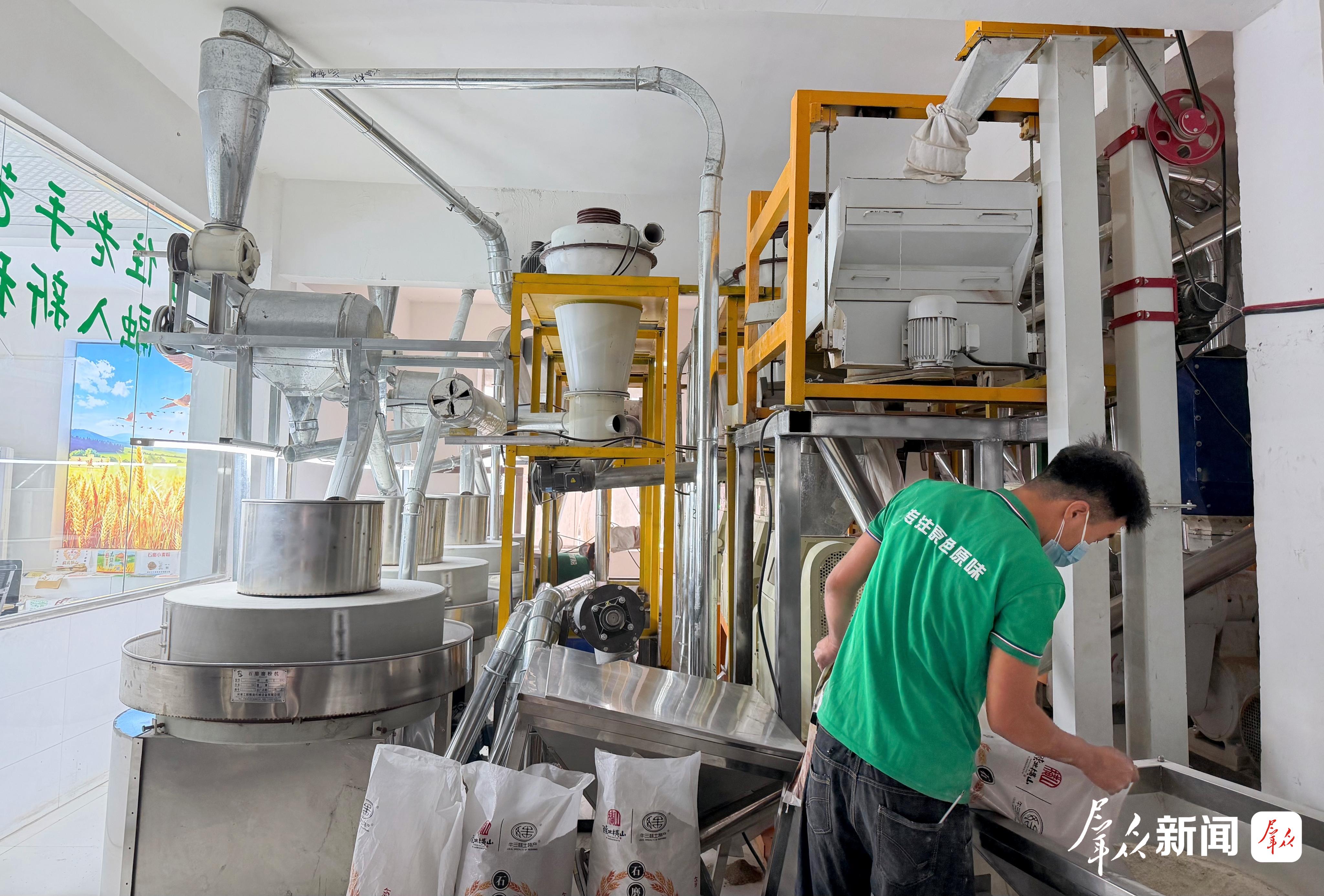 林专唛味石磨面粉厂工作人员正在添料磨面。